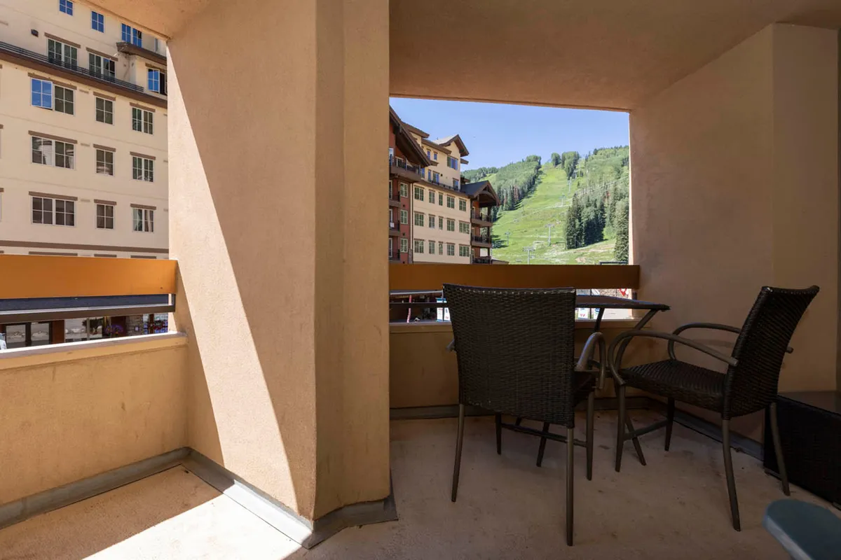 A tranquil balcony scene overlooking the mountains, with comfortable seating and views of the surrounding architecture. The inviting setup suggests a space to unwind after a day of village exploration, sharing moments with loved ones while taking in the scenery.