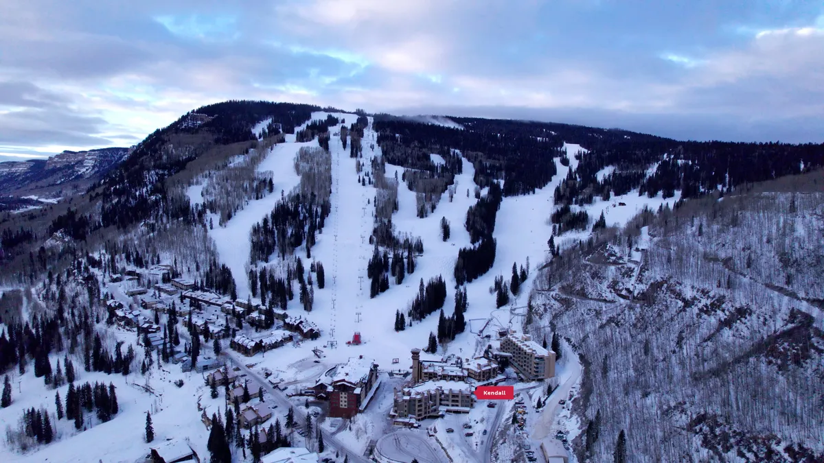 This exterior image features snow-covered trees, ski slopes, and the lodging facilities nestled in a winter wonderland. The view captures the fresh mountain air and proximity to outdoor adventures, inviting viewers to imagine themselves exploring the vibrant village and enjoying the snowy landscape.